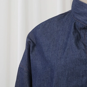 Detailed close-up of dark indigo denim shirt with orange topstitching and texture