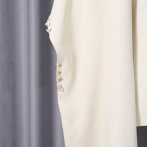 Detail of cream blazer sleeve with metallic rings, pearls and transparent bead accents