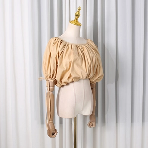 Detail of apricot cropped puff sleeve blouse with elastic neckline and drawstring cuffs