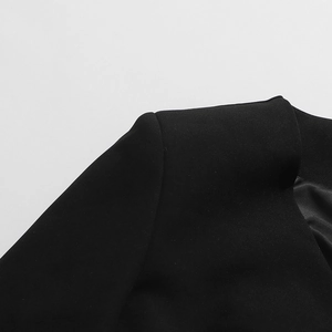 Gros plan sur les épaulettes et la texture tissée d'un manteau long noir pour femme