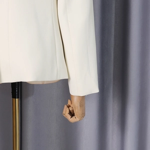 Detail showing the woven texture and clean seams of the white long-sleeve suit jacket