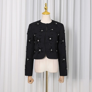 Detail of black tweed jacket featuring floral bead embroidery and elegant white accents