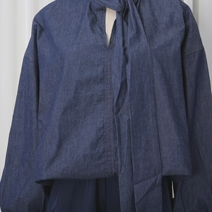 Close-up of dark blue denim shirt featuring bow-tie collar and red contrast stitching