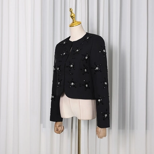 Detailed macro shot of 3D floral beading and pearl accents on black tweed jacket