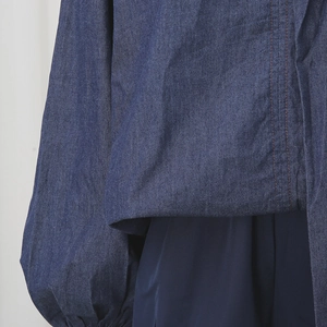 Detailed view of dark blue denim set featuring orange contrast stitching and lantern sleeves