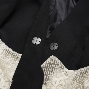 Vue détaillée de dentelle blanche sur tissu noir avec des boutons en métal argenté élégants