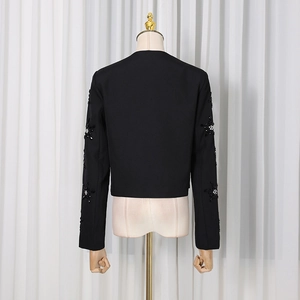 Detail of floral 3D beadwork with white crystals on the back of a black suit jacket sleeve