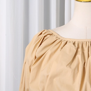 Detailed view of apricot blouse featuring pleated neckline and smooth cotton texture