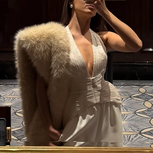 Détail d'une robe plissée à licou blanc avec un châle en fausse fourrure marron
