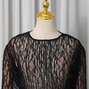 Detailed close-up of intricate black floral lace pattern on a sheer long-sleeve top
