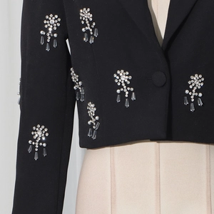 Detailed view of luxury rhinestone flower embroidery on a black tailored women suit jacket
