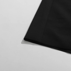 Détail de l'ourlet du manteau en dentelle noire avec coutures précises et tissu mat