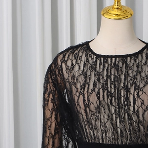 Close-up of intricate floral lace texture and sheer mesh on black slim fit top