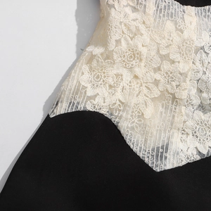 Détail de broderie en dentelle florale cousue sur tissu noir pour ce manteau long