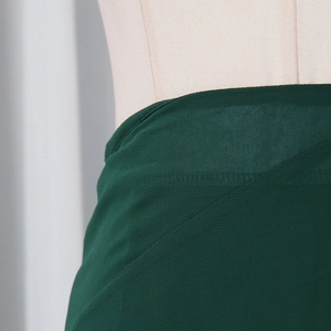 Detail shot of dark green ruffled skirt waist with criss-cross layered fabric and stitching