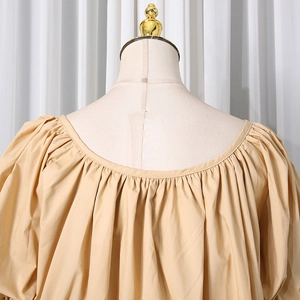 Detail of apricot puff sleeve blouse with pleated neckline on a mannequin