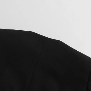 Détail de la couture d'épaule impeccable sur une veste longue en dentelle noire de luxe