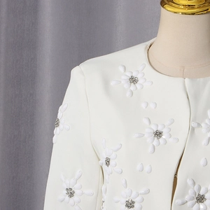 Detailed close-up of white jacket featuring 3D floral petals and silver crystal beading