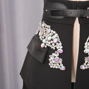 Close-up of black A-line skirt waist featuring heavy rhinestone decor and leather belt