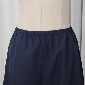 Detail shot of the elastic waistband on navy blue casual pants with flexible pleats