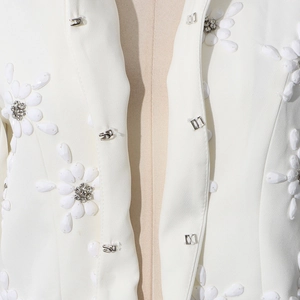 Detail of white blazer featuring 3D floral sequins, rhinestones and hidden hook closure