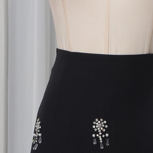 Detail of black high-waisted skirt with exquisite rhinestone and pearl floral accents