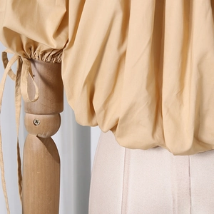 Detail of light brown lantern sleeve with elegant self-tie cuff design on women blouse