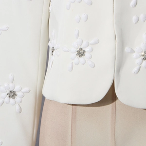 Close-up of white blazer detailing with exquisite pearl and rhinestone floral embroidery