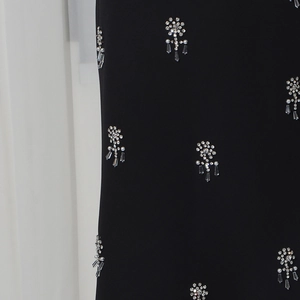 Detail of handcrafted floral beadwork with pearls and crystals on black fabric