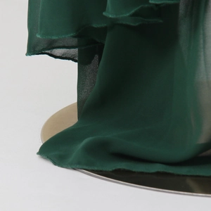 Detailed macro view of dark green layered chiffon ruffles with fine edge stitching