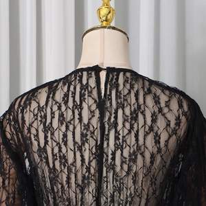 Close-up of black floral lace texture and teardrop back button detail on women's top