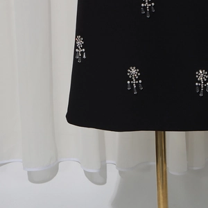 Detailed close-up of rhinestones and crystal drop charms on elegant black fabric