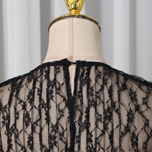 Macro view of delicate black floral lace fabric with a single button closure detail