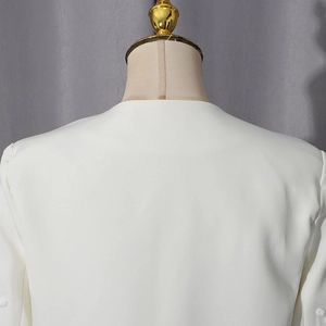 Detailed close-up of the clean round neckline and smooth shoulder seams of a white suit jacket