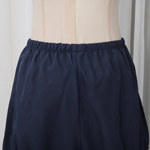Close-up of dark blue elastic waistband on smooth fabric shorts with uniform pleats