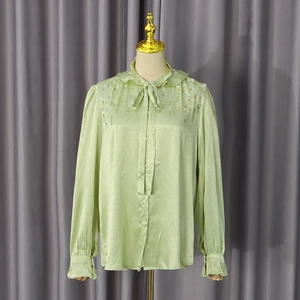 Detail of light green sequin shirt with ruffled bow collar and elegant satin texture