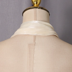 Détail de l'encolure dos nu plissée champagne avec texture soyeuse sur un mannequin
