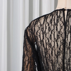 Detailed view of black lace top featuring floral patterns and a back neck button closure