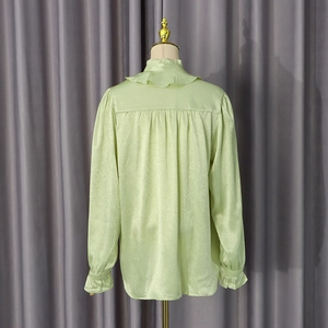 Detail view of the elegant ruffled collar and back pleated design on this satin shirt