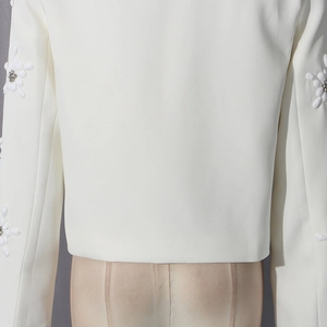Detail of white blazer back featuring structured cut and 3D floral petals with silver rhinestones