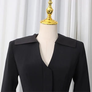 Detail of black blazer featuring a sharp V-neckline, wide lapels and slim waist design
