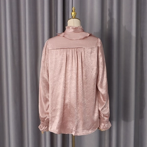 Detail view of pink satin shirt back featuring ruffled collar and pleated shoulder seams