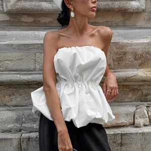 Détail du haut bustier blanc avec taille froncée élégante et ourlet à basque bouffante