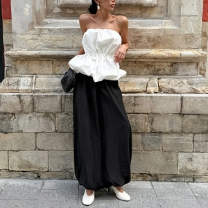 Détail du bustier blanc froncé à basque avec un pantalon noir taille haute à jambes larges