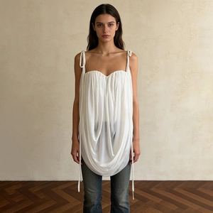 Detail of white pleated camisole with tie-shoulder straps and glossy textured fabric
