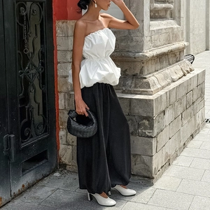 Détail d'un haut bustier blanc à ourlet bouffant et pantalon large noir en rue