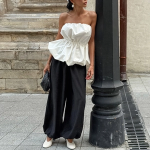 Détail d'un haut bustier blanc à ourlet bulle et d'un pantalon large à taille haute noir