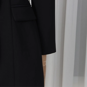 Detail view of the black blazer showing premium fabric texture and flap pocket stitching