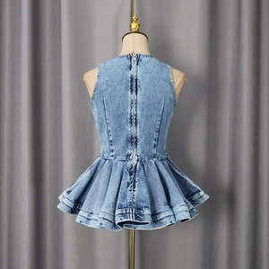 Detail of light blue denim peplum top showing back zipper and ruffled hem on a mannequin