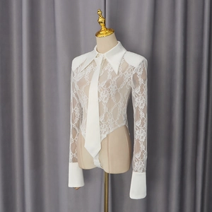 Detail of white lace bodysuit with shirt collar and tie showing delicate floral textures